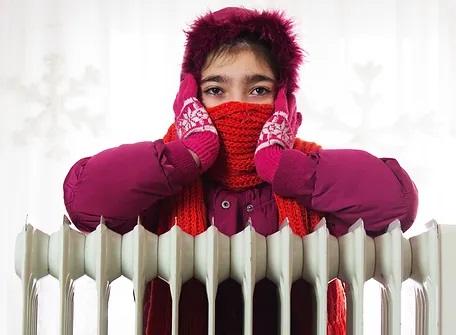 A lady dressed warm due to cold radiators